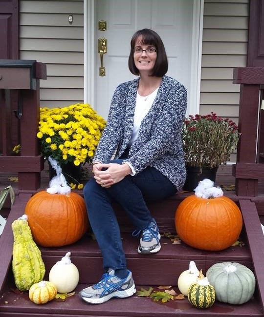 Teri Smith sitting on steps with pumpkins and fall flowers